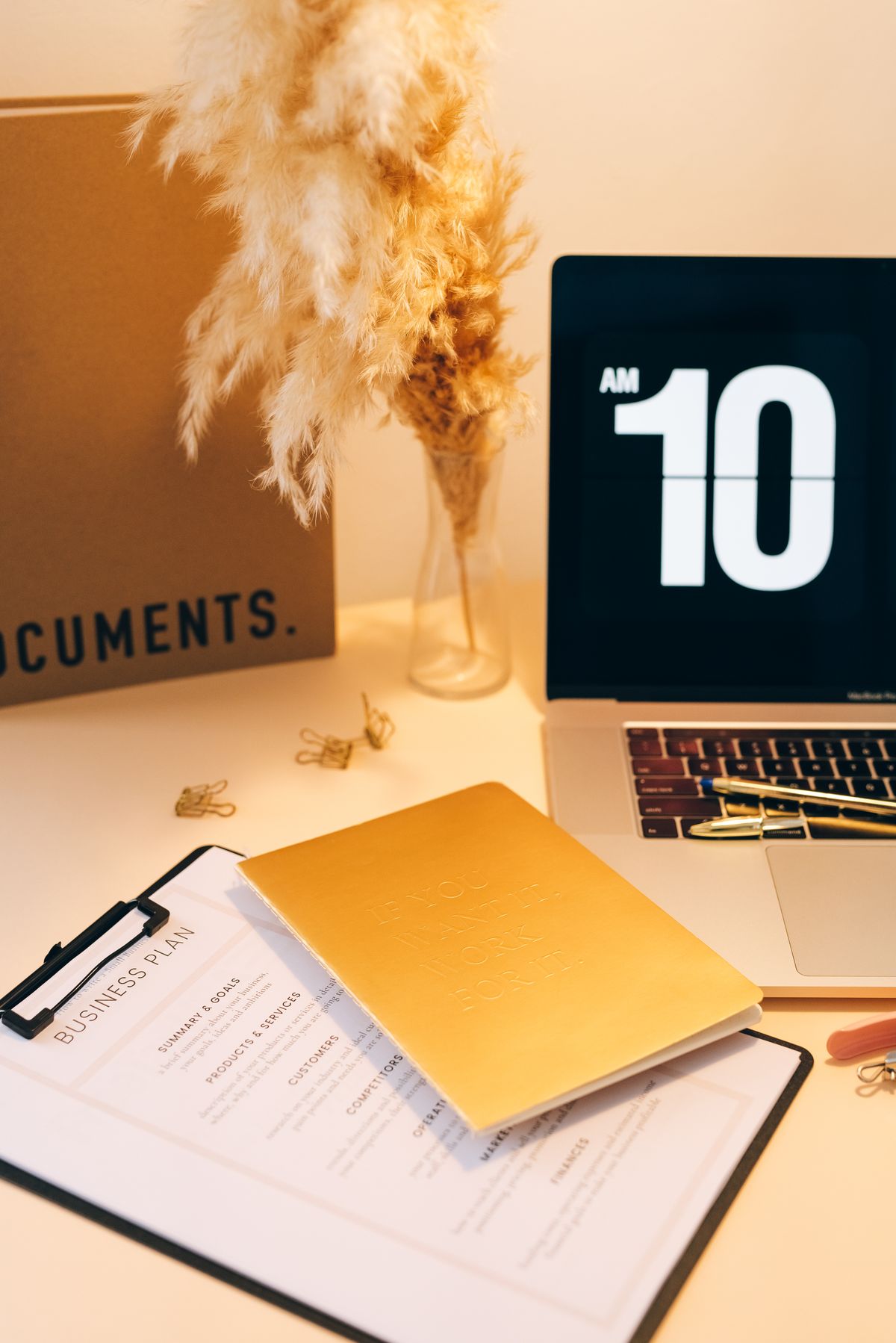 Documentos, un cuaderno y un portátil en una mesa de trabajo.